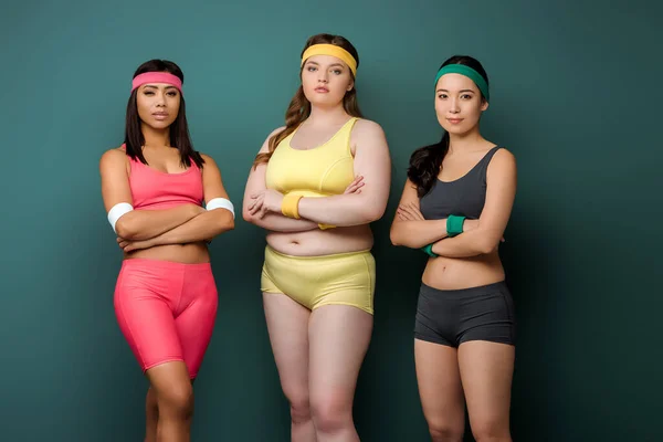 Sportswomen with crossed arms looking at camera on green background — Stock Photo