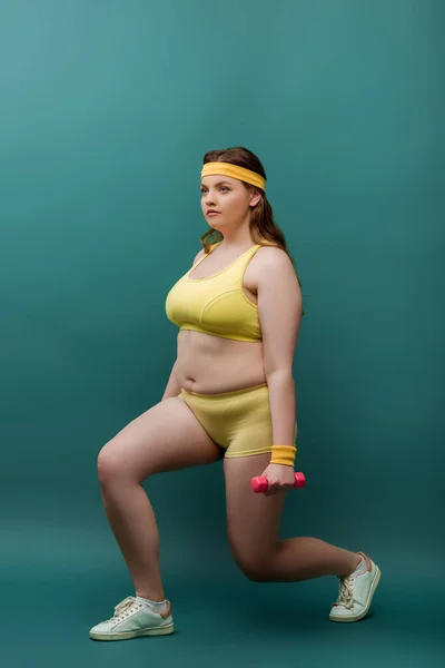 Plus Size Sportswoman Training mit Kurzhanteln auf grünem Hintergrund — Stockfoto