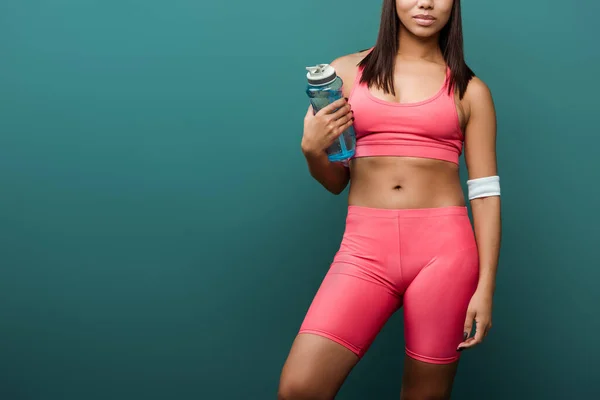 Cropped view of african american sportswoman with sports bottle isolated on green — Stock Photo