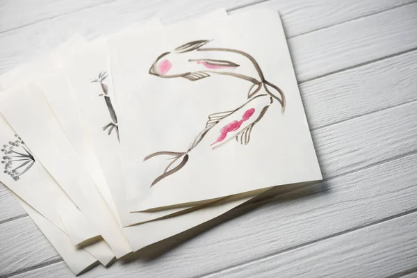 Hochwinkelaufnahme von Papier mit japanischer Malerei auf Holzoberfläche — Stockfoto