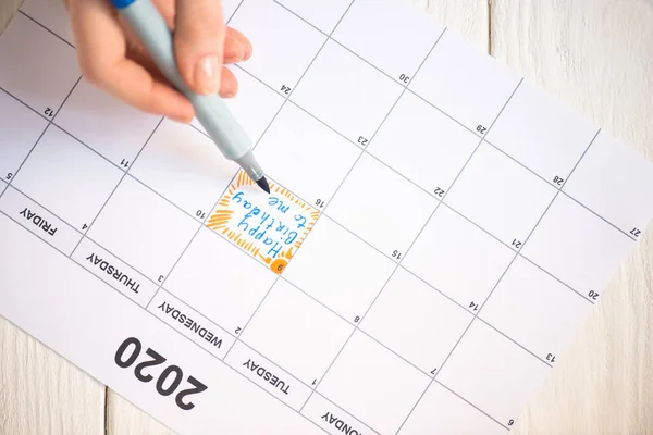 Vista cortada de mulher apontando com caneta marcador no feliz aniversário para mim lettering no calendário de tarefas com inscrição 2020 em fundo de madeira — Fotografia de Stock