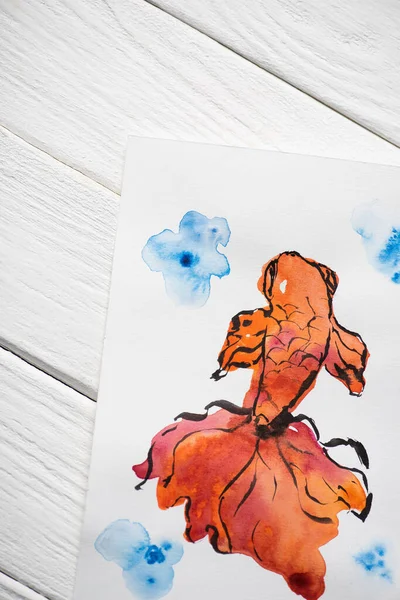Вид сверху на бумагу с японской росписью оранжевой рыбой на деревянном фоне — стоковое фото