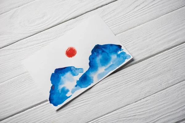 Vista superior de papel com pintura japonesa com nuvens e sol sobre fundo de madeira — Fotografia de Stock