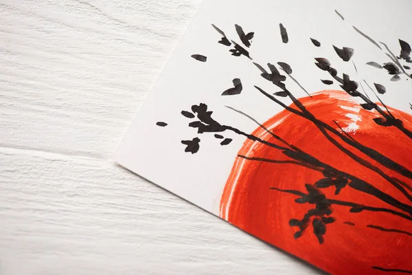 Vue du dessus du papier avec peinture japonaise avec soleil rouge et branches sur fond en bois — Photo de stock