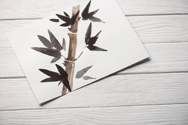 Vista superior de papel con pintura japonesa con bambú y hojas sobre fondo de madera - foto de stock