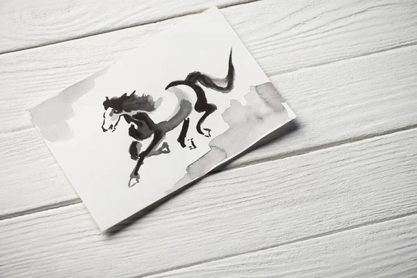 Вид сверху на бумагу с японской росписью лошади на деревянном фоне — стоковое фото