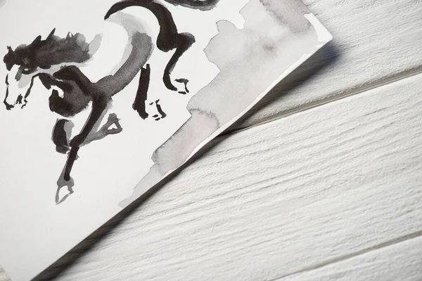 Вид сверху на бумагу с японской росписью лошади на деревянном фоне — стоковое фото