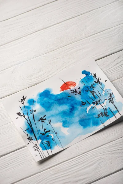 Hochwinkelaufnahme des Papiers mit japanischer Malerei mit Himmel, Ästen und Sonne auf Holzgrund — Stockfoto