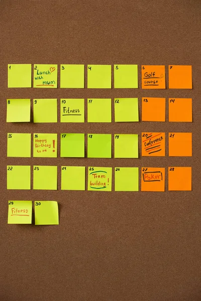 Top view of yellow and orange sticky notes on brown background — Stock Photo