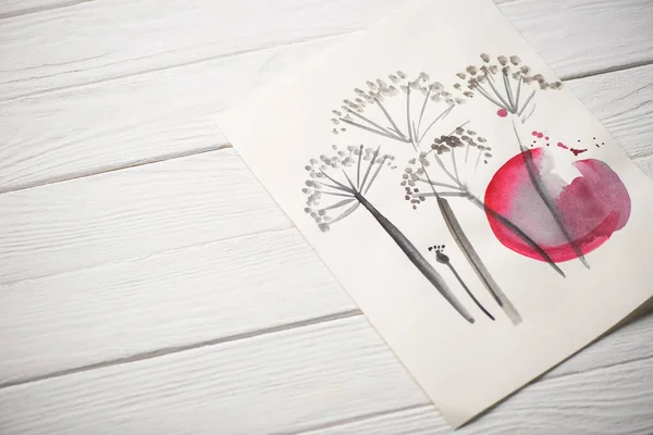 High angle view of paper with japanese painting with flowers and pink circle on wooden background — Stock Photo