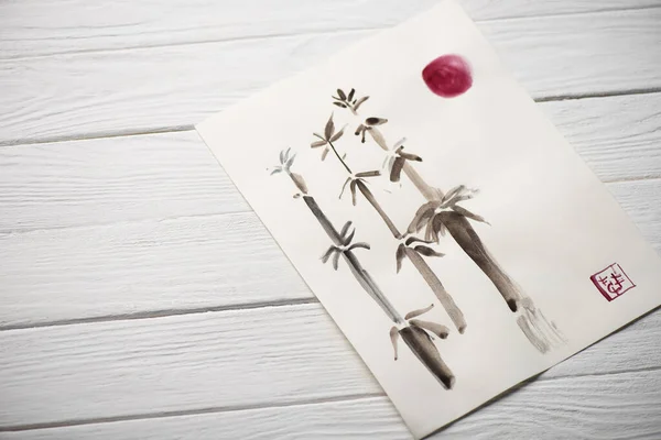 High angle view of paper with japanese painting with bamboo, sun and seal on wooden background — Stock Photo