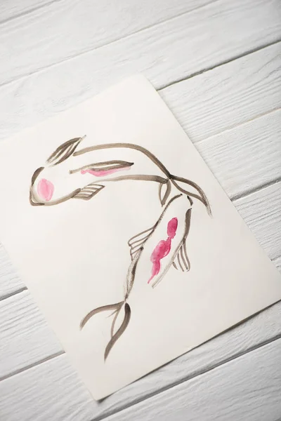 Hochwinkelansicht des Papiers mit japanischer Malerei mit Fischen auf Holzgrund — Stockfoto