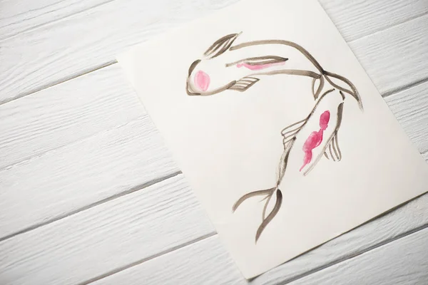 Hochwinkelaufnahme des Bildes mit japanischer Malerei mit Fischen auf hölzernem Hintergrund — Stockfoto