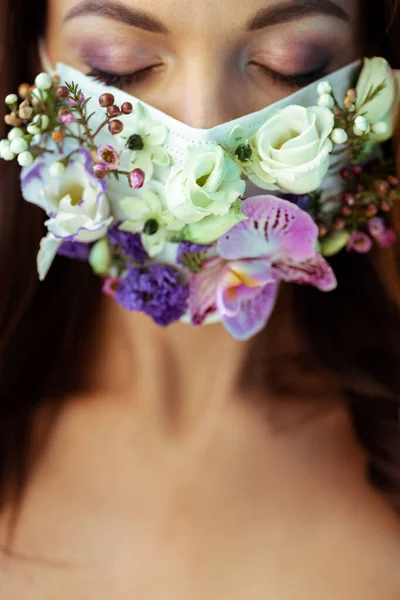 Mujer joven con los ojos cerrados en la mascarilla floral - foto de stock