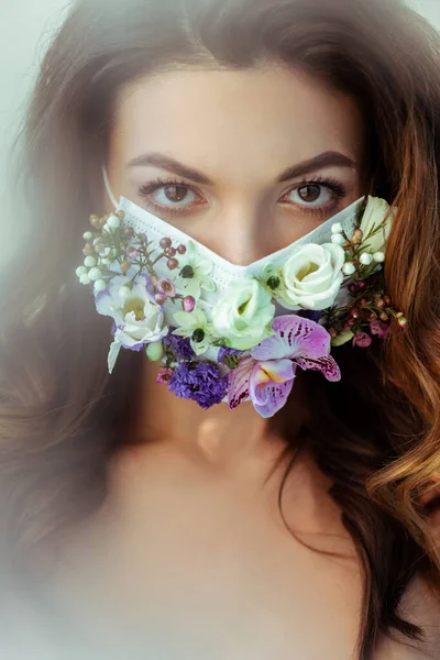 Enfoque selectivo de la mujer atractiva en la máscara facial floral mirando a la cámara - foto de stock