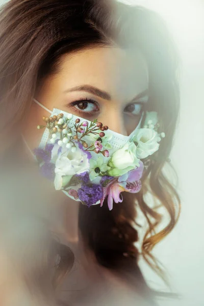 Selektiver Fokus der Frau mit floraler Gesichtsmaske, die in die Kamera auf Weiß blickt — Stockfoto