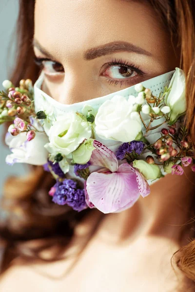 Foyer sélectif de la jeune femme dans le masque facial avec des fleurs — Photo de stock