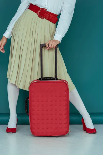 Abgeschnittene Ansicht eines stilvollen Mädchens, das mit Koffer auf blauem Grund steht — Stockfoto