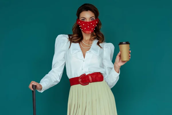 Модная девушка в красной маске держит кофе, чтобы пойти изолированы на синий — стоковое фото