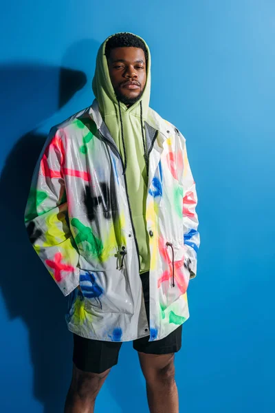 Fashionable african american man posing in colorful futuristic look on blue — Stock Photo