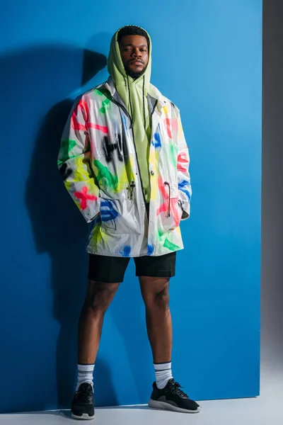 Elegante bonito homem afro-americano posando em colorido olhar futurista em cinza e azul — Fotografia de Stock