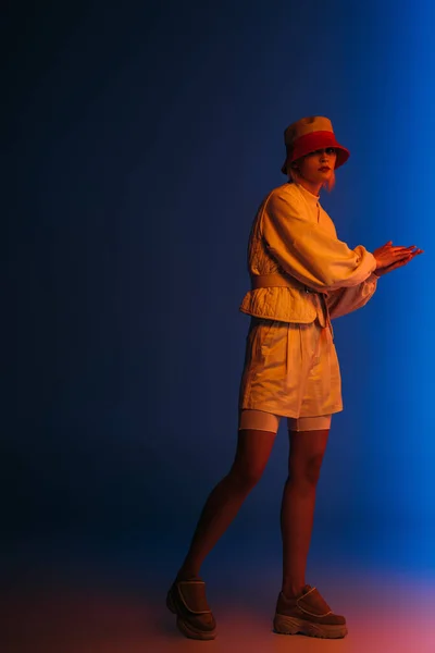 Attraente ragazza elegante in posa in look futuristico e cappello su blu scuro — Foto stock
