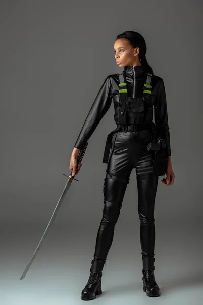 Atractiva mujer afroamericana futurista con espada sobre gris - foto de stock