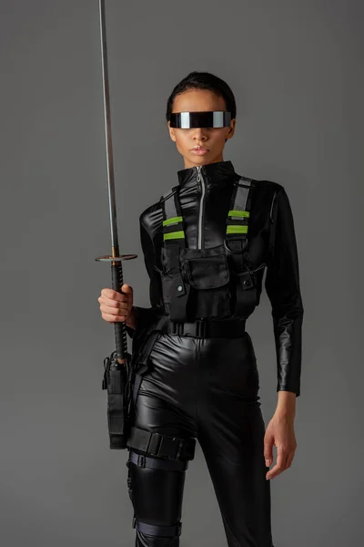 Attraktive futuristische afrikanisch-amerikanische Frau in Brille mit Schwert isoliert auf grau — Stockfoto