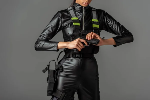 Vista cortada de mulher futurista afro-americana recarregando arma isolada em cinza — Fotografia de Stock
