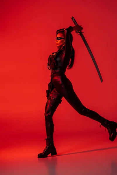 Futurista mujer afroamericana en gafas con espada sobre fondo rojo - foto de stock