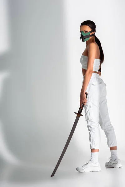 Futurista Africano americano mulher em máscara de segurança com espada no fundo branco — Fotografia de Stock