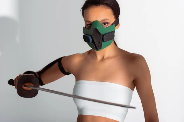 Futuriste afro-américaine en masque de sécurité avec épée sur fond blanc — Photo de stock