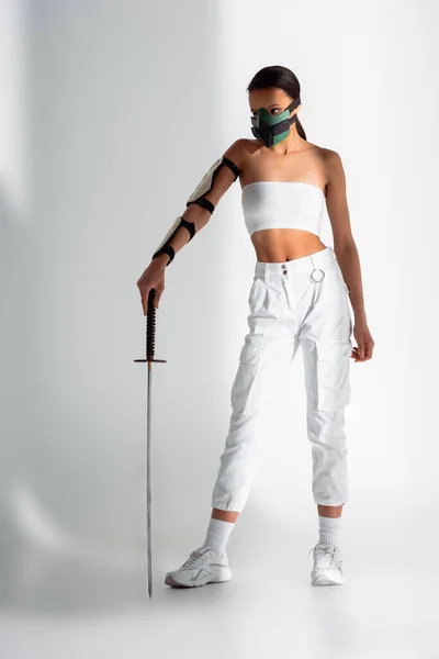 Футуристична афроамериканська жінка в масці безпеки з мечем на білому тлі — стокове фото