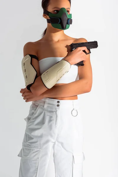 Futurista mujer afroamericana en máscara de seguridad con arma aislada en blanco - foto de stock