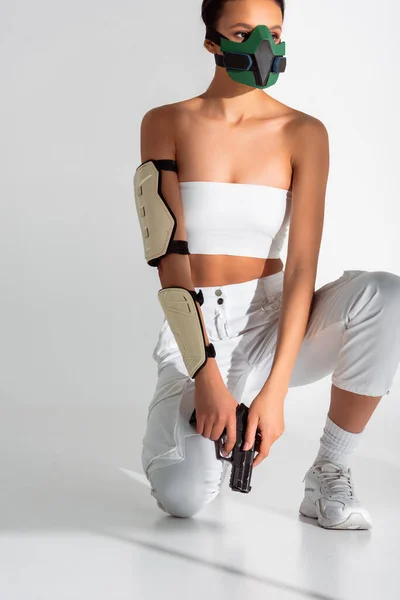 Футуристична афроамериканська жінка в масці безпеки з пістолетом на білому тлі — стокове фото