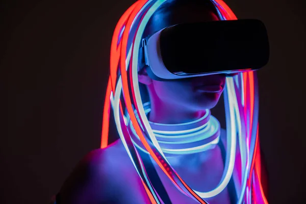 Futuristica donna afroamericana in auricolare vr e illuminazione al neon — Foto stock