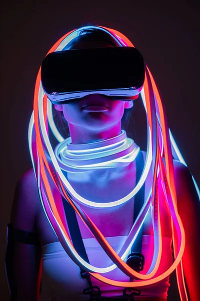 Futuristica donna afroamericana in auricolare vr e illuminazione al neon — Foto stock