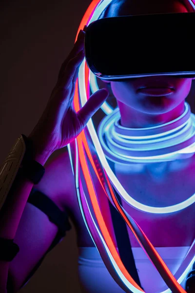 Futuristica donna afroamericana in auricolare vr e illuminazione al neon — Foto stock