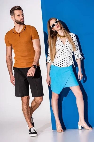 Beautiful fashionable couple posing in summer clothes and sunglasses on grey and blue — Stock Photo