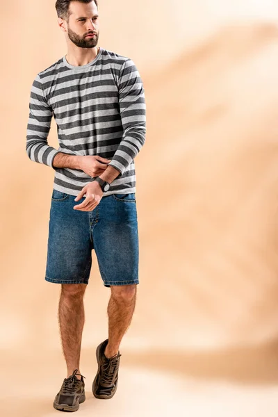Bearded young man posing in striped sweatshirt on beige — Stock Photo