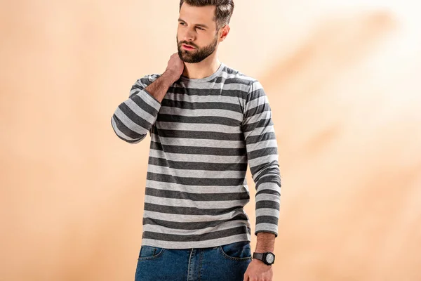 Stylish bearded man posing in striped sweatshirt on beige — Stock Photo