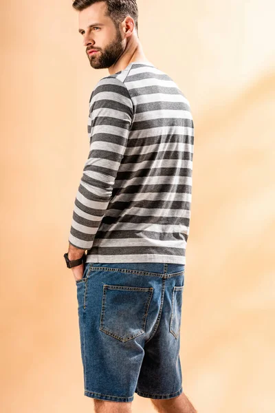 Handsome bearded man posing in striped sweatshirt on beige — Stock Photo