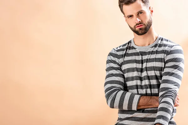 Schöner stylischer junger Mann posiert in gestreiftem Sweatshirt auf beige — Stockfoto