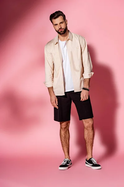 Stylish handsome bearded man posing in summer shirt and shorts on pink — Stock Photo