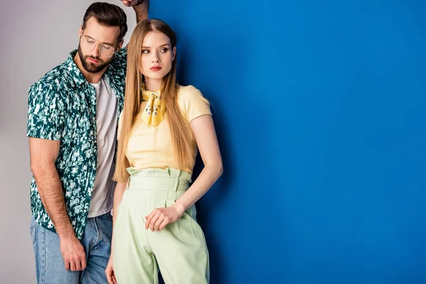 Jeune couple à la mode posant en vêtements d'été sur gris et bleu — Photo de stock