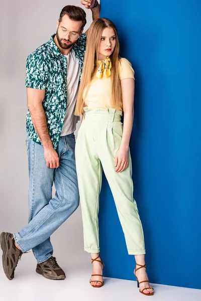 Beautiful fashionable couple posing in summer clothes on grey and blue — Stock Photo