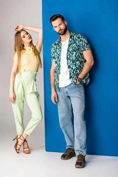 Модна молода пара позує в літньому одязі на сірому і синьому — стокове фото