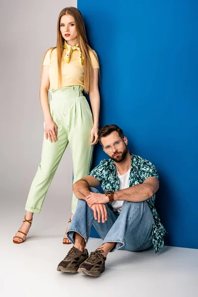 Beau couple à la mode posant en vêtements d'été sur gris et bleu — Photo de stock