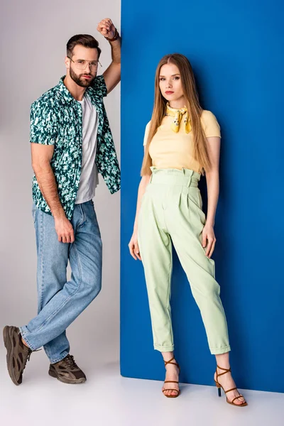 Stylish young couple posing in summer clothes on grey and blue — Stock Photo