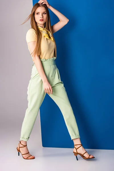 Chica elegante posando en pantalones verdes de verano y sandalias de tacón en gris y azul - foto de stock